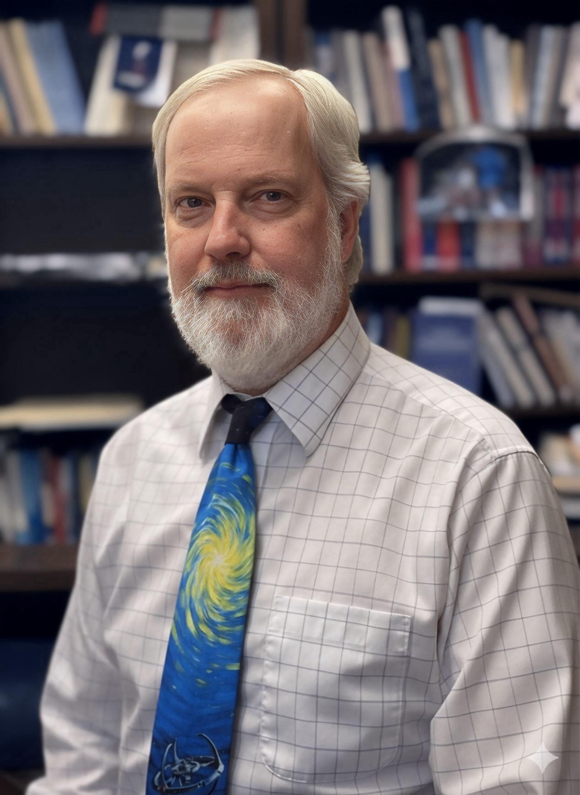 John Heyrman portrait wearing a tie and a dress up shirt with background of bookshelves.